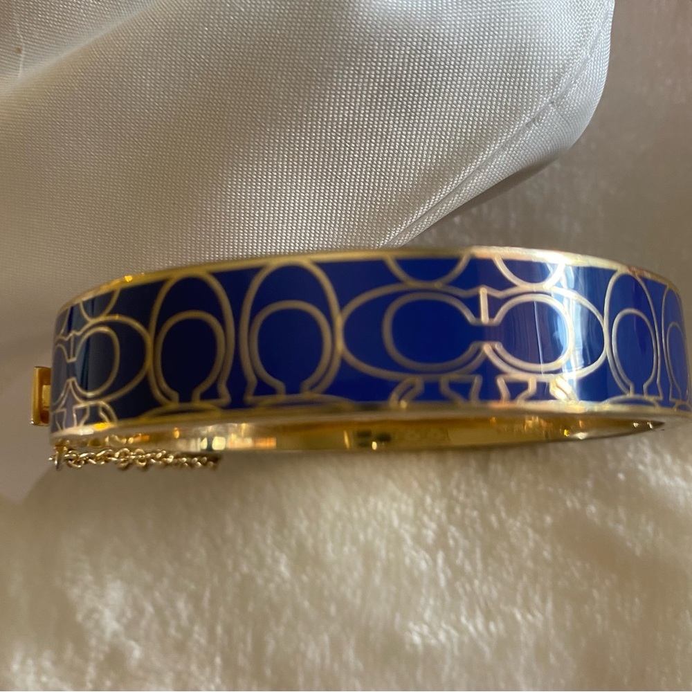 Coach Signature C enamel bangle hinged closure bracelet with safety chain.